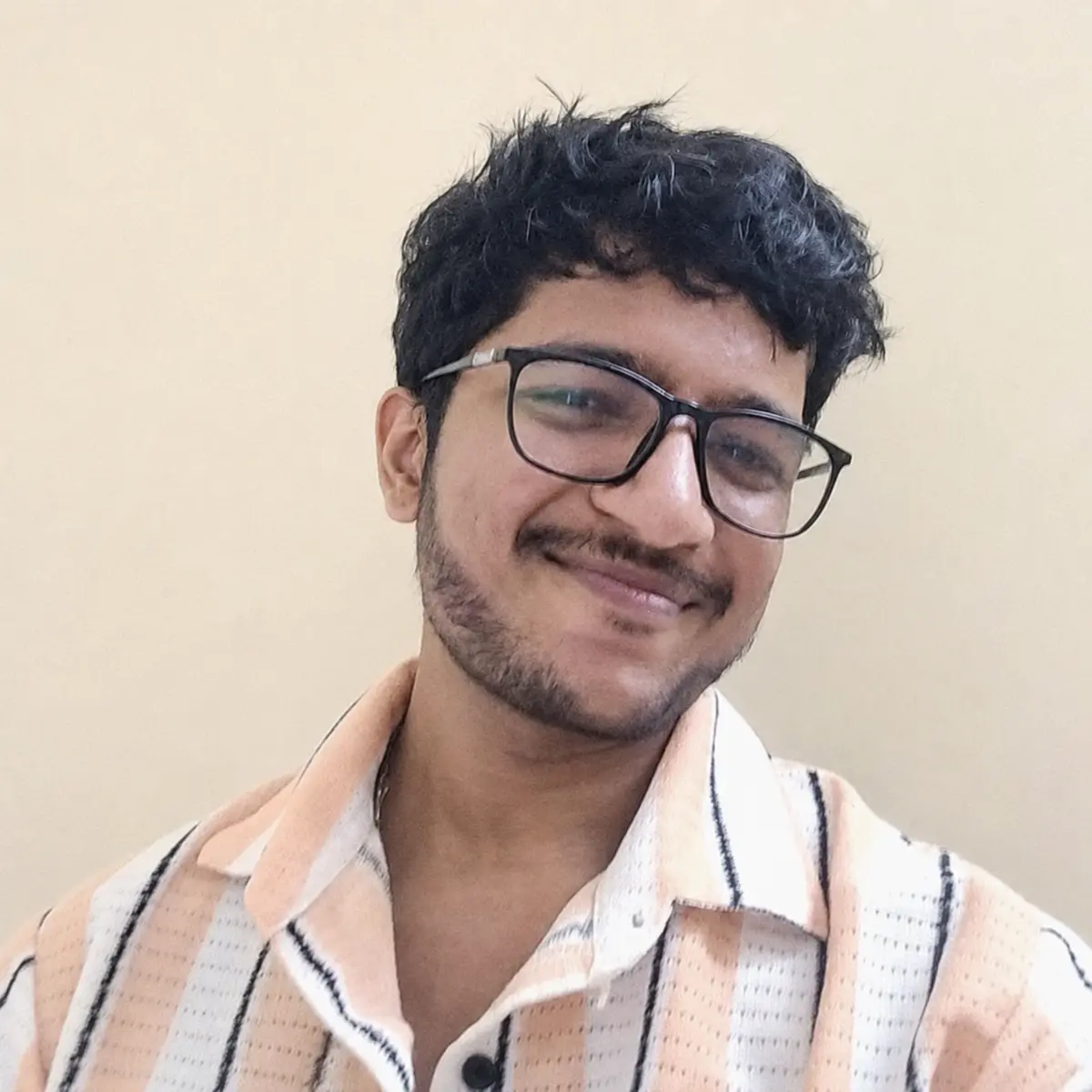 Kumar Sambhav smiling in a light striped shirt